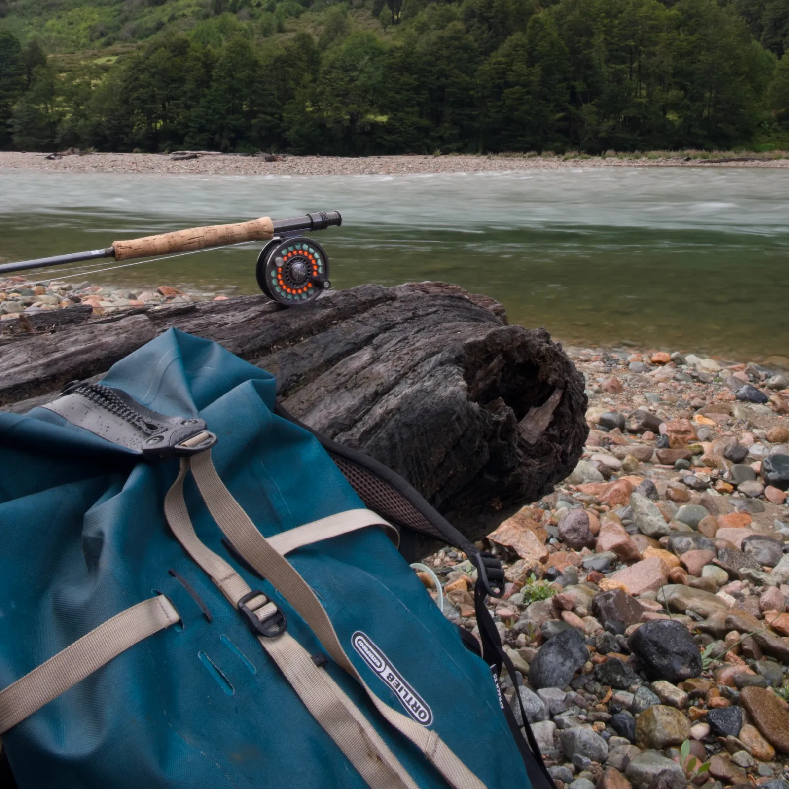 Ortlieb Atrack 35 on a riverbank beside a fly rod and reel