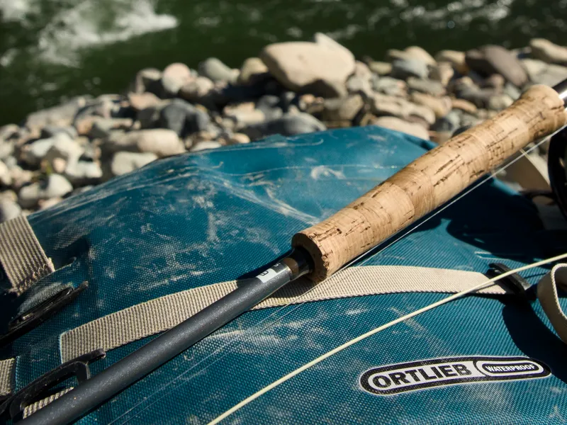 Fly rod and reel resting on a well-worn Ortlieb Atrack by the river