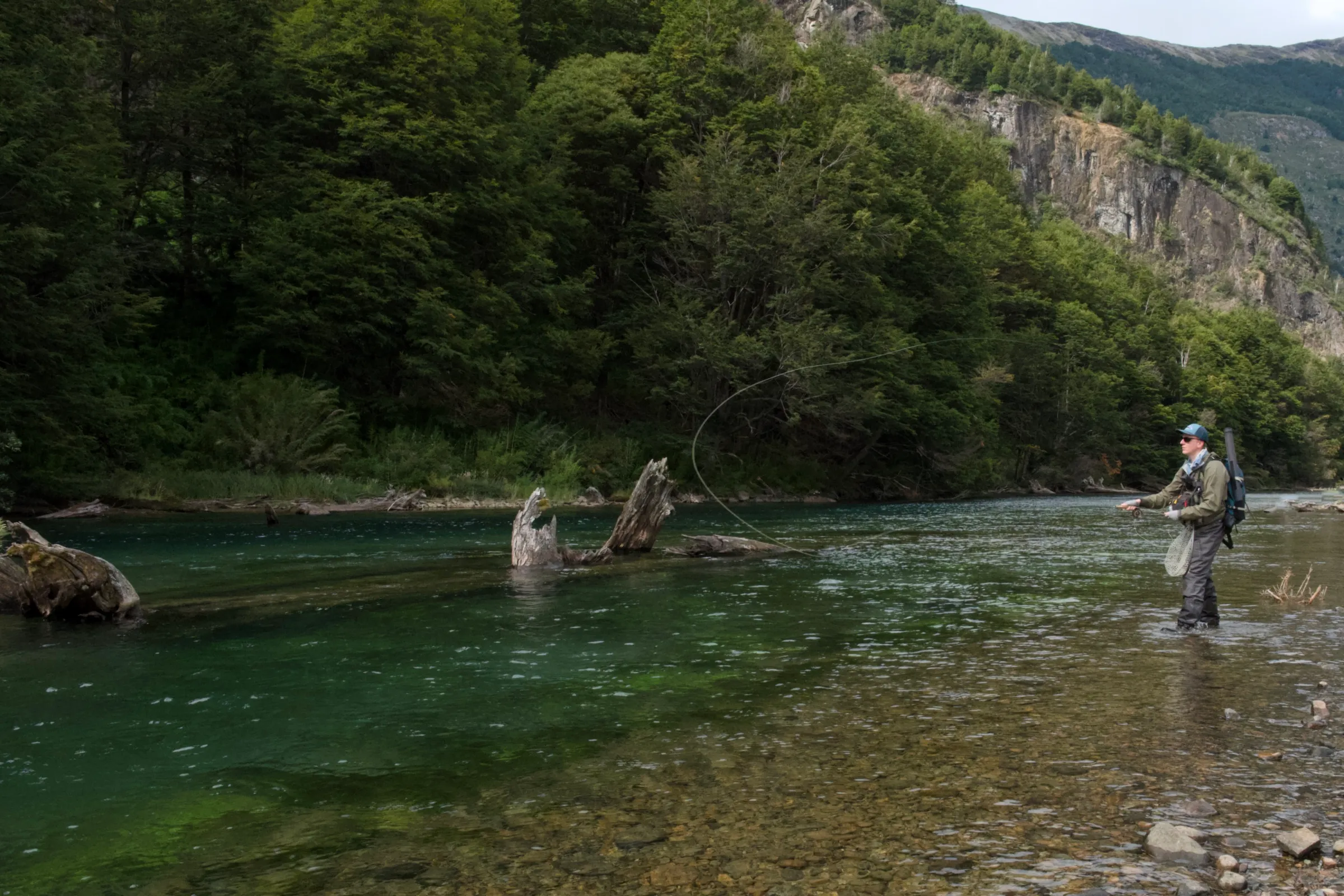 Fly fisher casting on the clear green water of the upper Rio Paloma